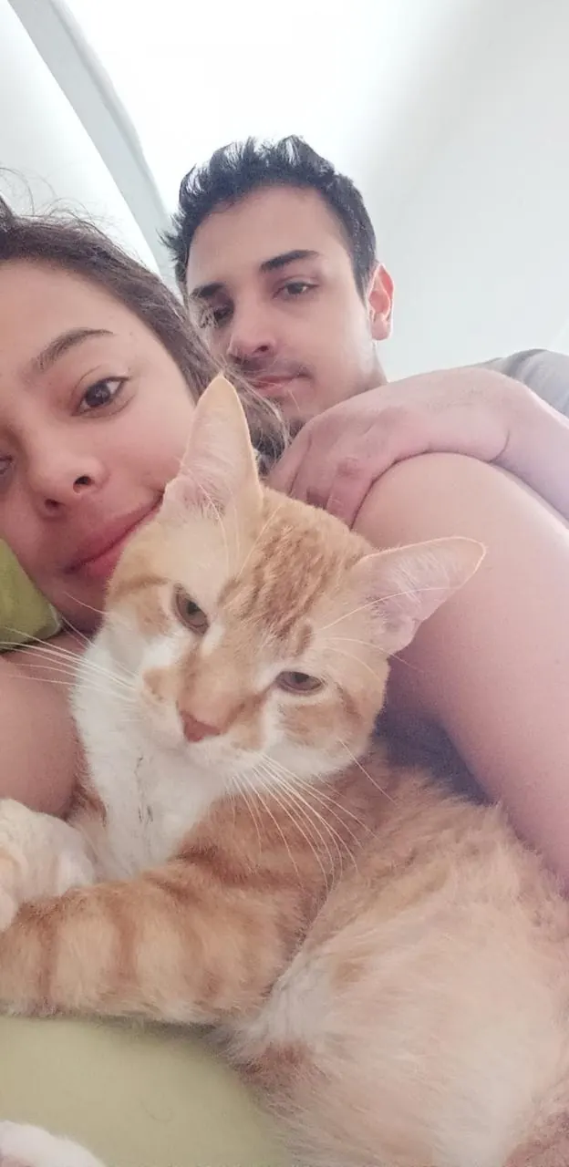 Sparky en brazos de la pareja, los tres juntos en el sofá